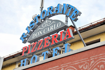 Außenfassade der Pizzeria Don Carlo mit Leuchtschild in Völkermarkt